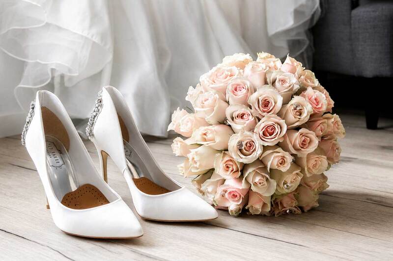 Detalle del vestido de novia, zapatos y ramo capturado durante preparativos de boda.